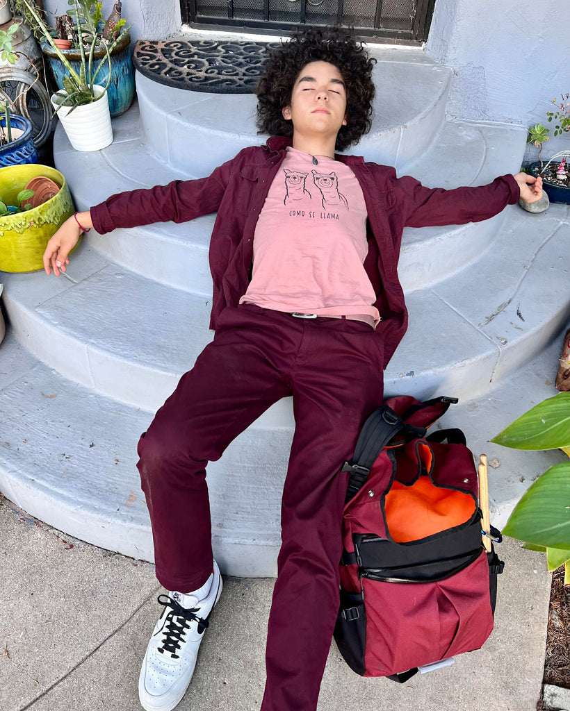 Commuting to School with Asa laying on the ground with his backpack